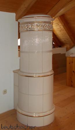 Bei diesem runden Kachelofen, der als Säulenofen mit einer elektrischen Heizung ausgestattet ist, wurde mit Ofenkacheln von Leutschacher gebaut.
